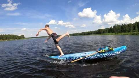 4K of a man running on and diving off a SUP paddleboard on a sunny summers day Stock Footage 157106493