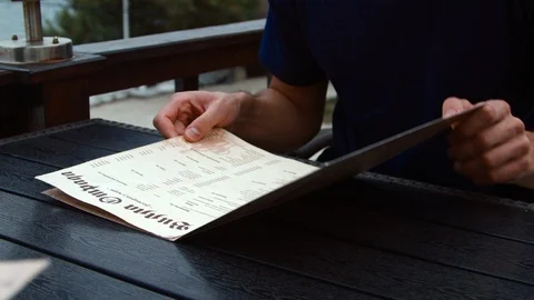 4K A man sits at a table in a cafe and reads a menu Stock-Footage 99933250