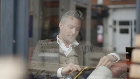 4K Man Sitting Alone In Cafe Using Computer Tablet &amp; Drinking Coffee Stock Footage 75692523
