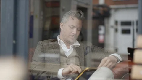 4K Man Sitting Alone In Cafe Using Computer Tablet &amp; Drinking Coffee Stock Footage 75692621