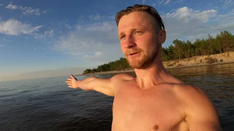 4K man spinning while standing on a beach showing the area and falling in water Stock Footage 157106836