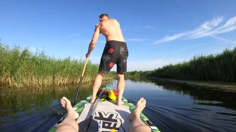 4K of a man standing and paddling on a SUP paddleboard in a swampy river Stock Footage 157106946