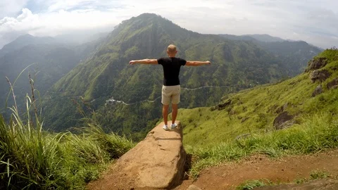 4K man standing on edge of cliff stretching hands and enjoying nature Stock Footage 116416703