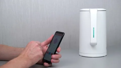 4K.the man turns on the kettle using an application on his smartphone.smart home Video stock 171279854
