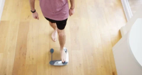 4K Man unhappy about weight gain stepping on the scale &amp; frowning at camera Stock Footage 88557784