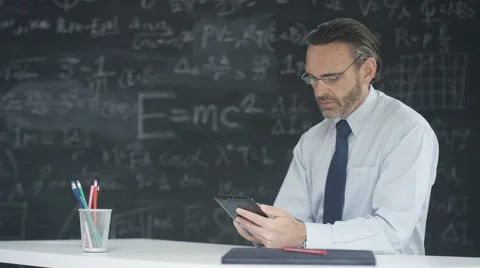 4K Man using computer tablet in classroom, studying math formulas on blackboard Stock Footage 67879416