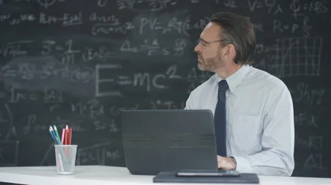 4K Man using laptop in classroom, studying math formulas on blackboard Stock Footage 67879438