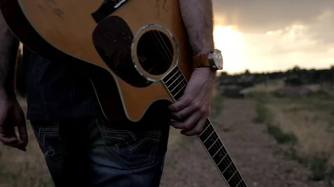 4k of Man walking with guitar at sunset Video stock 105086229