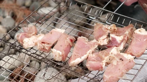 4K. A man's hand puts juicy pieces of meat on a metal grill. Close-up. Stock Footage 168850488