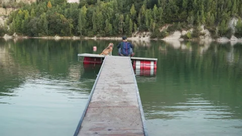 4K master and his beagle sitting at end of pier contemplating water surface 動画素材 155159705