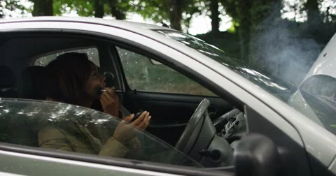 4k, A mechanic fixes a car while the car owner is busy applying make-up Stock Footage 68365551