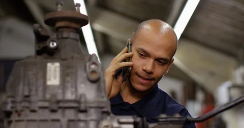 4K Mechanic looking at car engine &amp; giving advice to vehicle owner on the phone Stock Footage 103825268