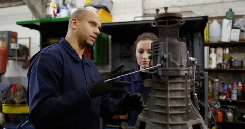 4K Mechanics in garage workshop having a discussion about car engine parts Stock-Footage 103053608