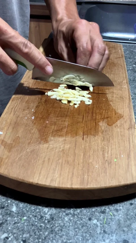 4K Medium Close Up Of A Man's Hand Chopping Garlic On A Wooden Board 库存影片 337224973