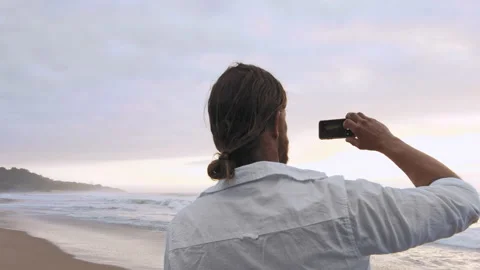 4k medium of happy man young taking photo on his smartphone app with dogs on bea Stock Footage 199619153