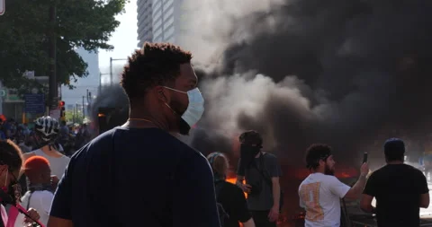 4K MEDIUM SHOT OF BLACK MAN WATCHING A CAR ON FIRE Video stock 131454623