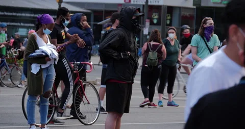 4K MEDIUM SHOT OF MASKED PROTESTORS STANDING IN THE STREET Video stock 131458237