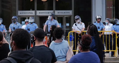 4K MEDIUM SHOT OF PROTEST LEADER PACING IN FRONT OF POLICE OFFICER BARRIER Stock Footage 131459123
