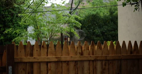 4K MEDIUM SHOT RACK FOCUS FROM FENCE TO TREES IN THE RAIN Stock Footage 131128331