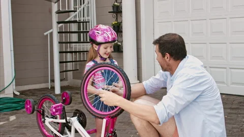 4k medium steadicam shot of father and daughter fixing a bike on a sunny day on Stock Footage 201095498