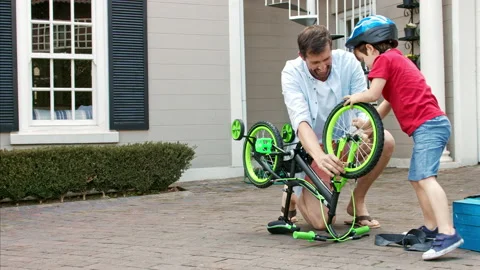 4k medium steadicam shot of father and son fixing a bike on a sunny day on home Stock Footage 201096071