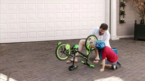4k medium steadicam shot of father and son fixing a bike on a sunny day on home Stock Footage 201097105
