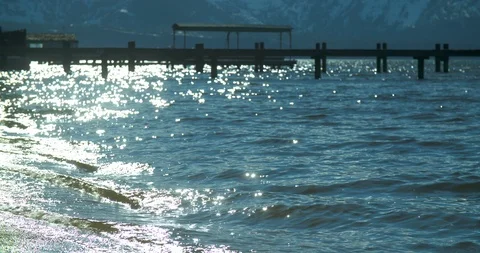 4k mild waves crashing on sandy beach with dock in background 動画素材 109258073