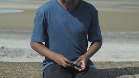 4K Mixed Race Boy Picking Up and Spinning a Toy on a Sunny Beach 库存影片 75956246