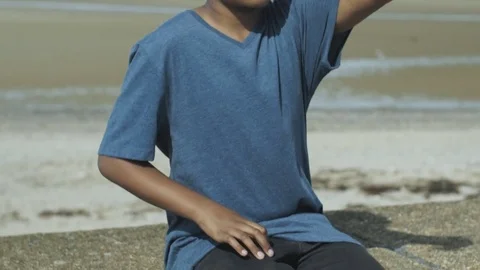 4K Mixed Race Young Boy Fumbling Dropping and Spinning Toy on Sunny Beach 库存影片 75956249