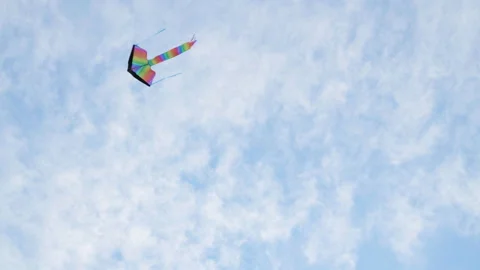 4K multi-coloured kite flying in blue cloudy sky fluttering under gusts of wind Stock-Footage 167028179