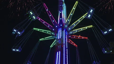 4K Multicoloured tall carousel spinning in black sky with fireworks 動画素材 148989152