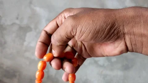 4K Muslim Hand Counting Orange Tasbih Beads During Islamic Dhikr Close Up Stock Footage 337123331