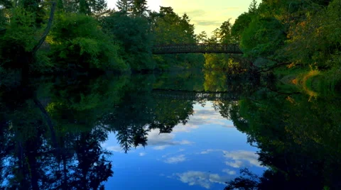 4K Natural Park River Stream, Calm Blue Water Surface and Bridge in Background Stock Footage 68726758