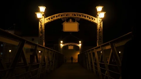 4k night static shot of an ancient metallic pedestrian bridge with silhouettes Stock Footage 124075521