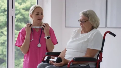 4K Nurse in care home showing elderly lady in wheelchair some exercises Stock Footage