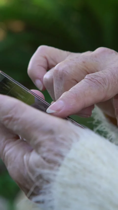 4K Old hands of Grandma using and looking at smart phone in the garden house Stock Footage 317576964