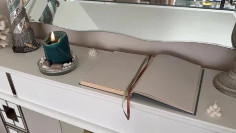 4K - Open Blank Journal Book And Burning Candle On White Fireplace Mantel Stock Footage 345347116