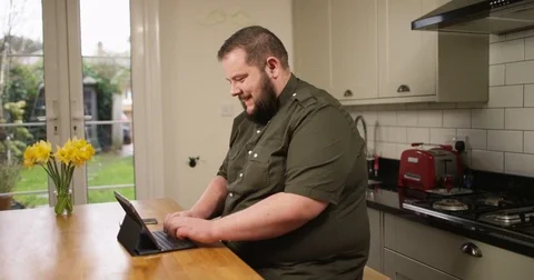 4k, An overweight man using tablet computer with keyboard &amp; stand. Stock Footage 74313770