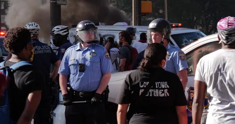 4K PAN COPS IN FULL GEAR GUARDING FIRE ON STREET AT PROTEST Stock Footage 131453744