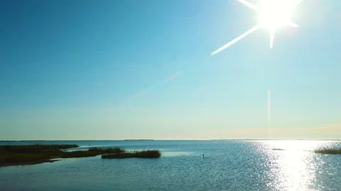 4K pan left to right past sun and bright reflection on waterway to Vidéo 142780448