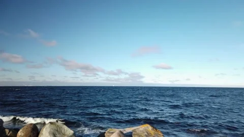 4K, Pan ocean, waves, rocky shore, clouds in blue sky, Oresund bridge horizon Stockbeeldmateriaal 147195287