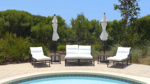 4K Pan of Pool Chairs Sitting Next to Pool and Plants Vidéo 111031887