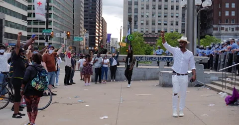 4K PAN OF PROTEST LEADER ADDRESSING A CROWD IN FRONT OF POLICE Stock Footage 131458795