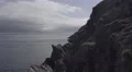 4k pan of rocky cliffs over the sea- boat floats on the ocean. Sunny day 4k or 4k+ Resolution