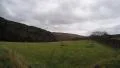 4K Pan of tree covered hills and green fields with grey and white clouds 4k or 4k+ Resolution