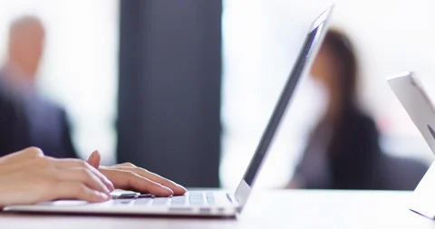 4K Panning shot with focus pull from hands typing on laptop to businesswoman Stock Footage 104121578