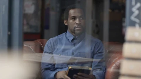4K Pensive Man Sitting Alone In Cafe, Looking Out Of Window &amp; Using Tablet Stock Footage 75717368
