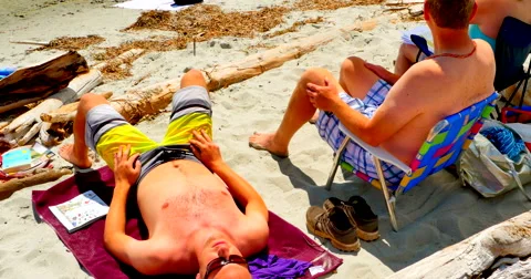 4K People Sunbathing on Sand Beach, People Enjoying Swimming in Background Stock Footage 61208272