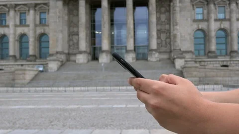 4K. Person using a smartphone near the Reichstag building, a landmark Stock Footage 100673152