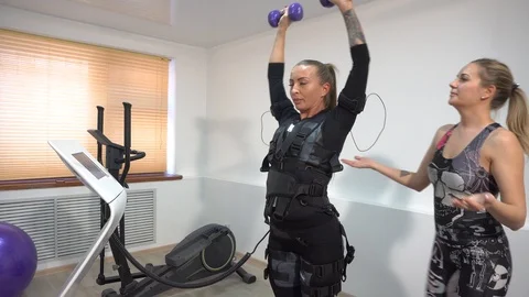 4k Personal trainer trains a beautiful girl to exercise with an EMS device Stock Footage 102362089